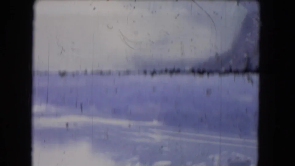 1964 8mm Niagara Falls aerial frame, heavily softened by exposure and mist, with river ice, dark frame edges, and visible film wear.