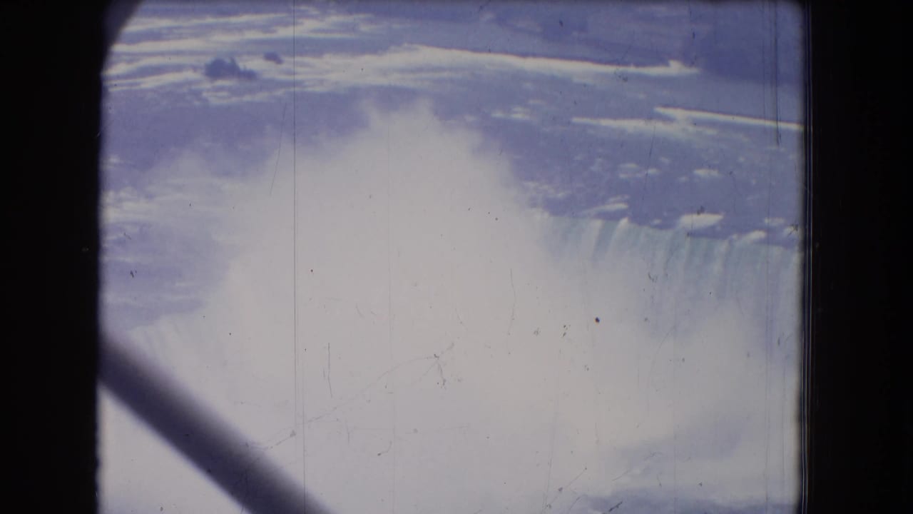 Niagara Falls appears through a dark central support and diagonal brace, with mist and river visible in the 1964 8mm frame.