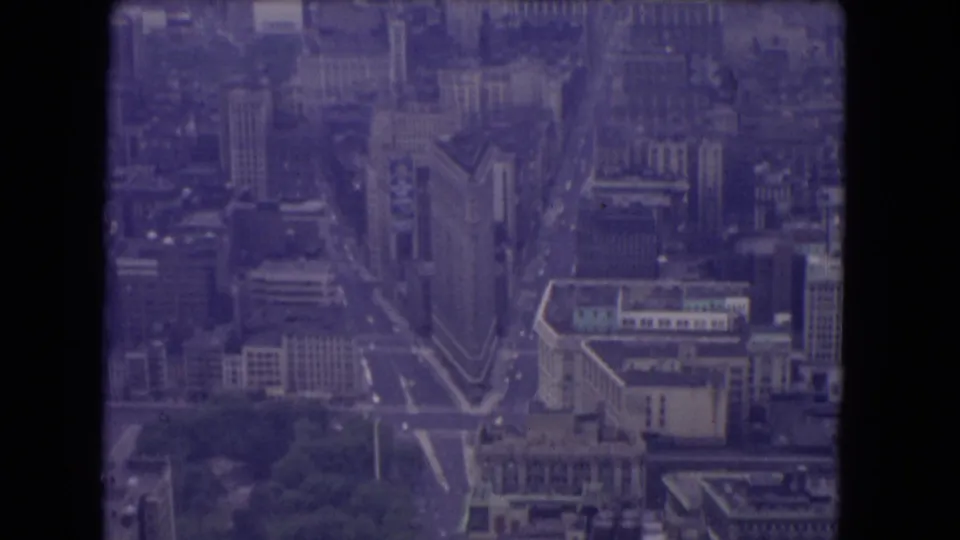 1960s 8mm aerial view that may show Manhattan with a triangular Flatiron-like building, surrounding high-rises, streets, and trees.