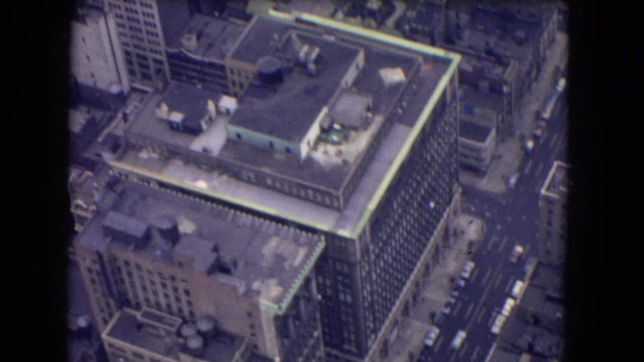 Aerial view of a large high-rise building beside city streets with cars.