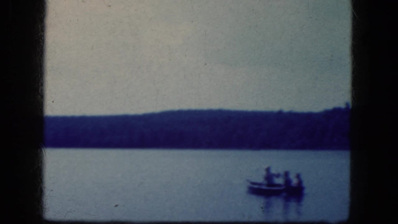 1964 8mm home-movie frame from the Niagara Falls, New York area showing a small boat with distant people on calm lake water.