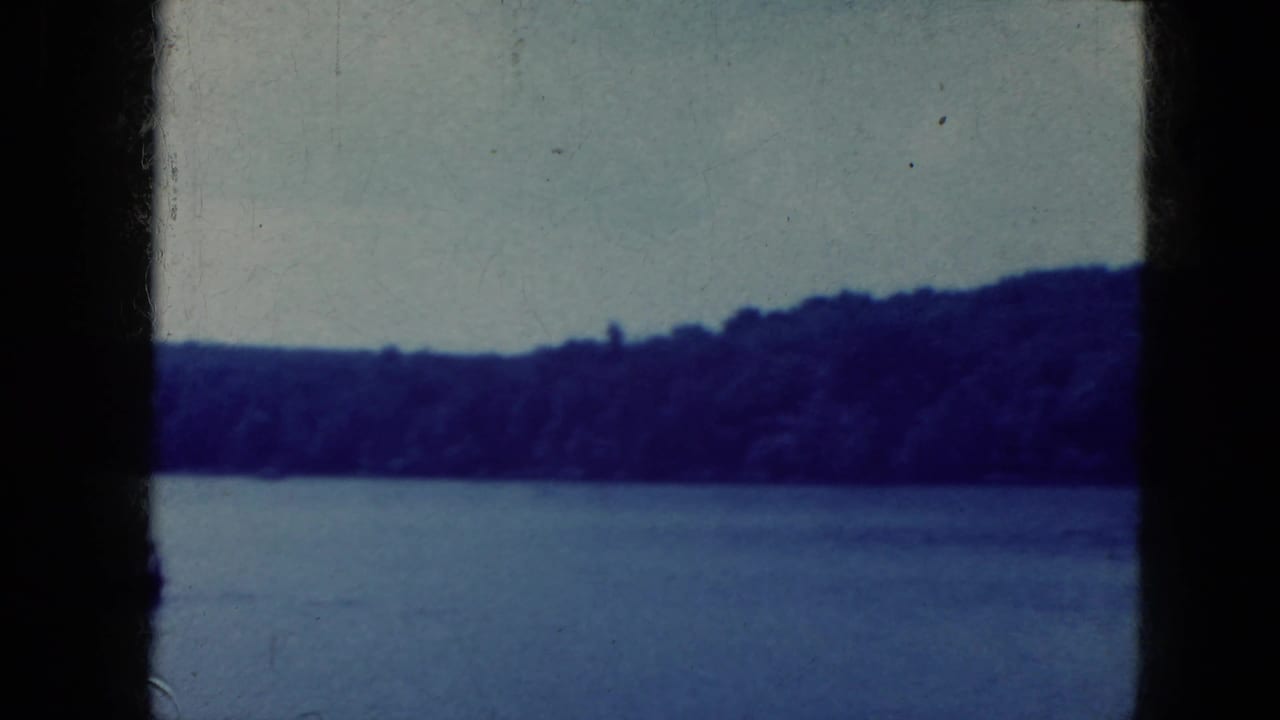 Blue-tinted water and forested shoreline under a pale sky within dark 8mm frame borders.