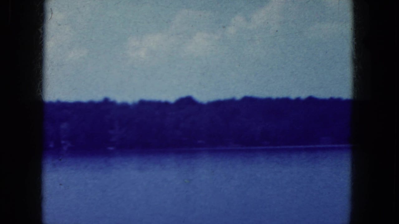 Blue lake and wooded horizon with a vertical dark film-strip divider at left.