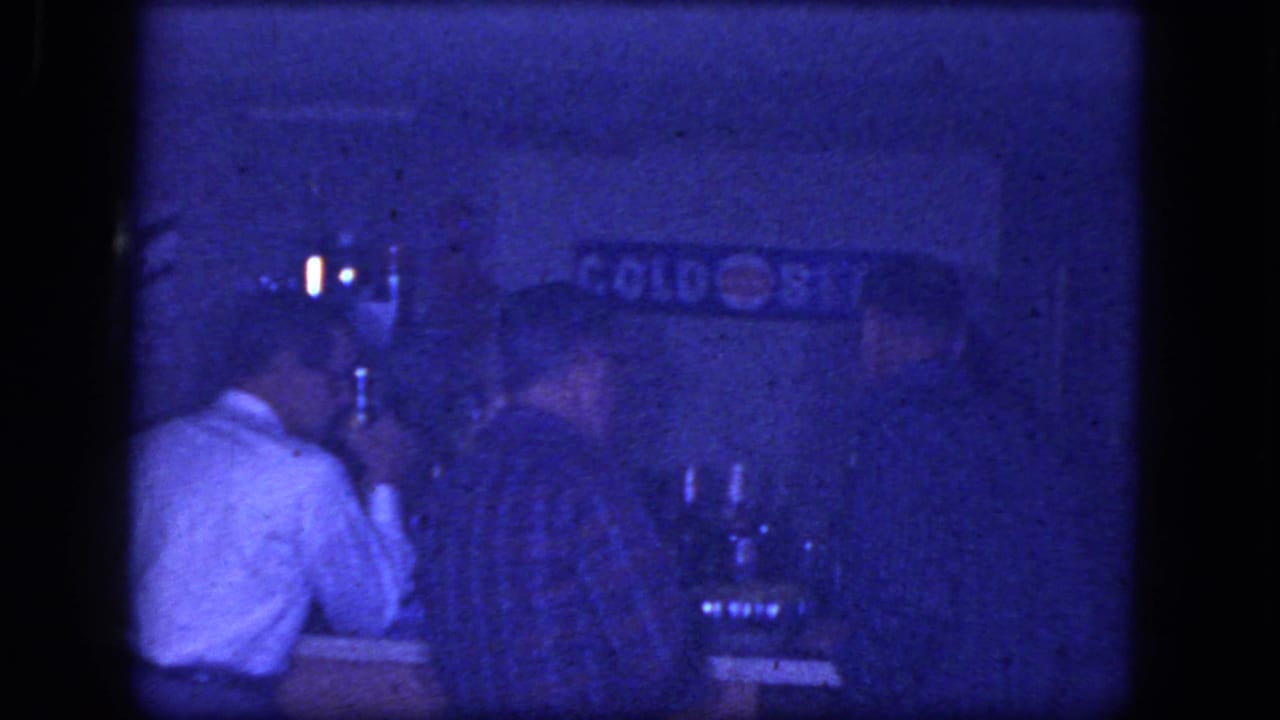 Men sit at the bar, including one in a white shirt and one in plaid.