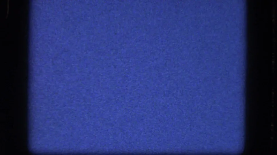 1964 8mm frame from the Niagara Falls reel showing a darker blue film field with gate shadowing, grain, and scattered specks.