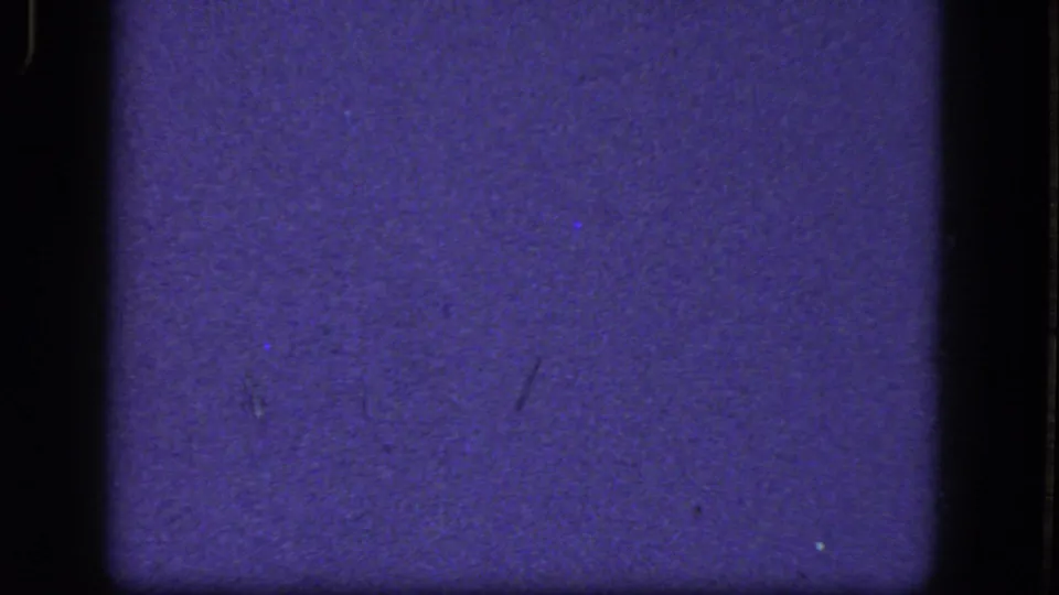 Aged 8mm frame from the 1964 clip showing a purple-blue cast, grain, and dark gate edges with no identifiable subject.