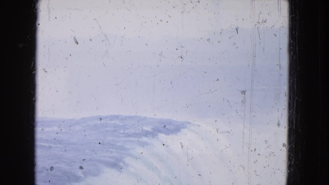 High-angle 1964 8mm view at Niagara Falls, with curved white water below, pale sky or mist above, and worn film texture visible.