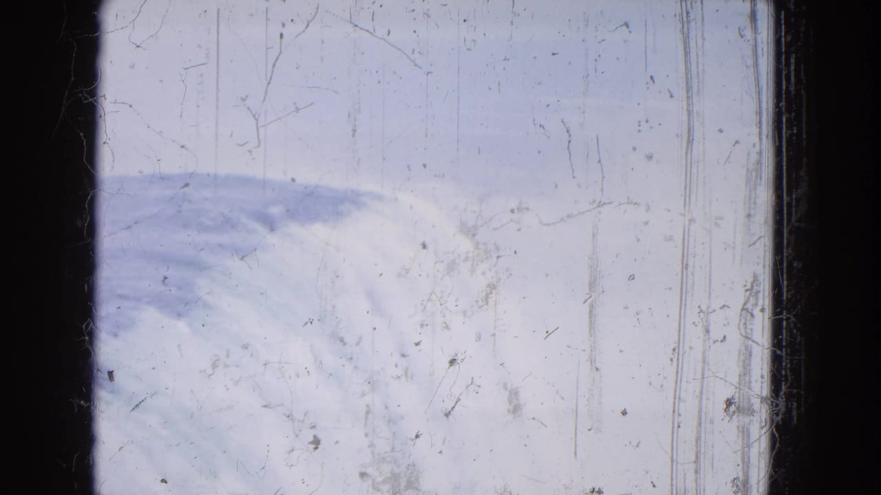 1964 Niagara Falls home-movie frame with water and foam crossing the lower edge, misty brightness, scratches, and dark film borders.
