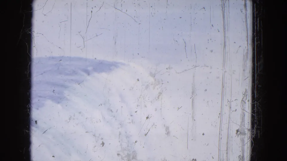 1964 Niagara Falls home-movie frame with water and foam crossing the lower edge, misty brightness, scratches, and dark film borders.