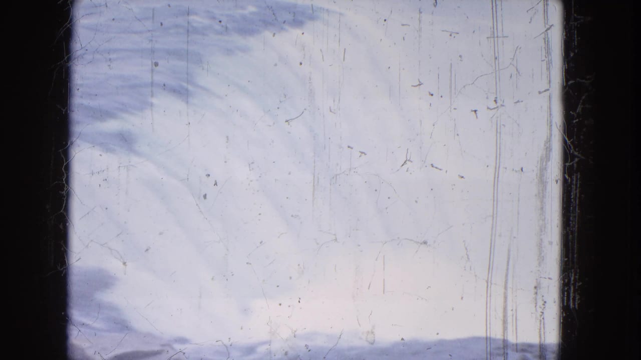 Broad pale view of waterfall spray and river surface with scratches and black film edge.