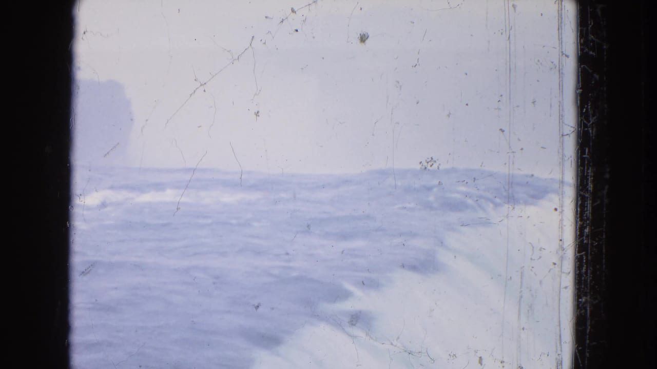 Distant 1964 8mm view of Niagara Falls water and mist, with dark gate edges and pronounced film wear.