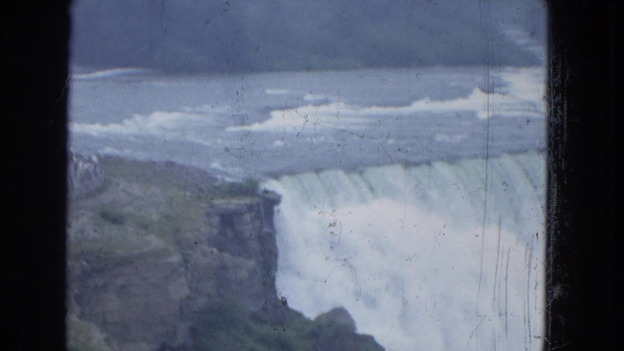 Wide waterfall and rocky edge with turbulent water above the drop.