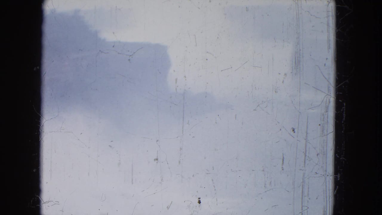 Pale storm clouds and mist seen through dark film-frame edges.
