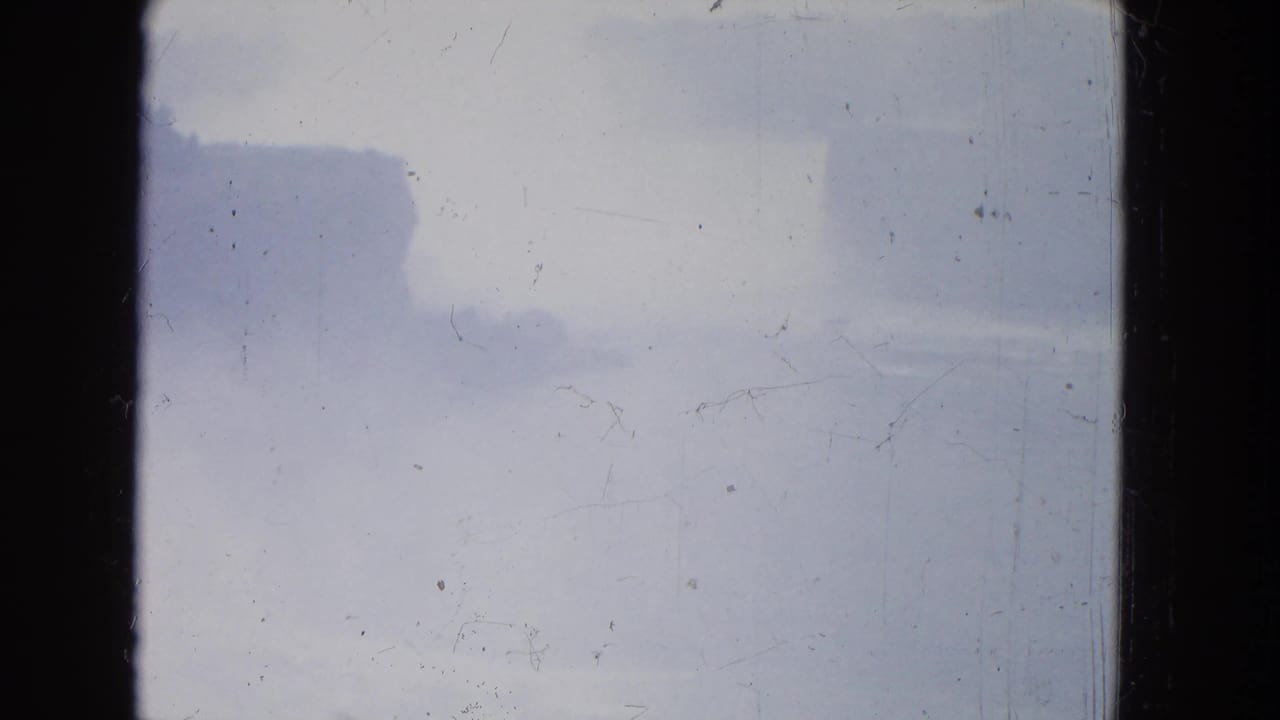 Misty Niagara Falls sky in a 1964 8mm frame, with faint cloud shapes and surface scratches.
