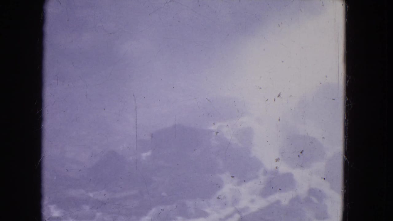 1964 Niagara Falls home-movie frame with low mist, dark cloud forms, and aged 8mm texture.