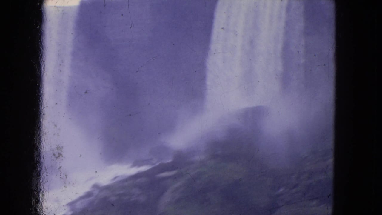 Visitor-shot 1964 Niagara Falls footage with a broad falling sheet of water, rocks below, heavy mist, and faded 8mm color.