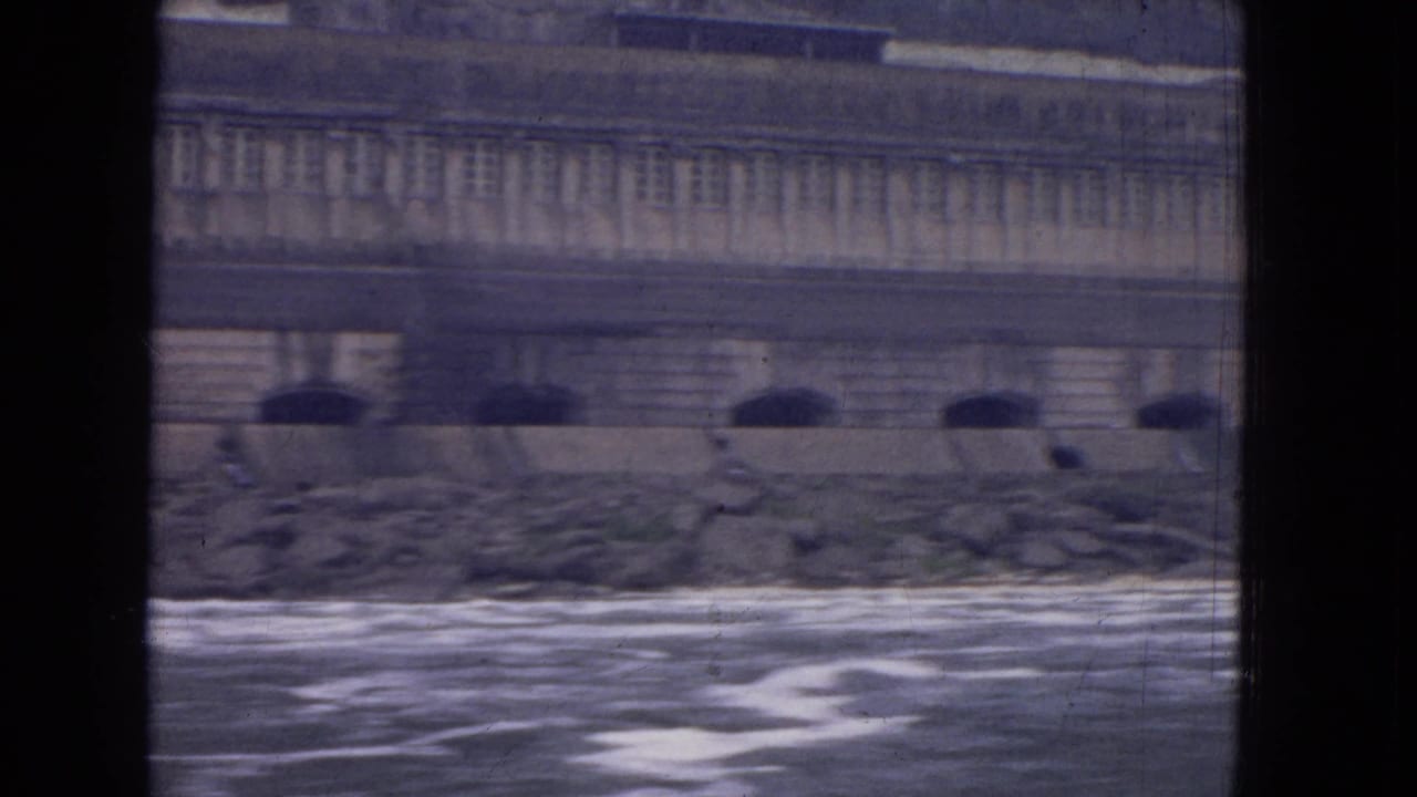 Turbulent water below a large stone building with rows of windows and arched openings.