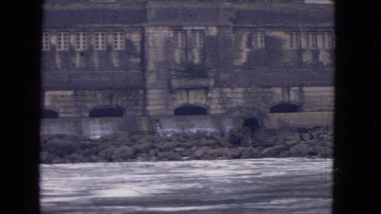 End frame of a 1964 Niagara River boat shot with choppy water and a weathered stone structure along the bank.