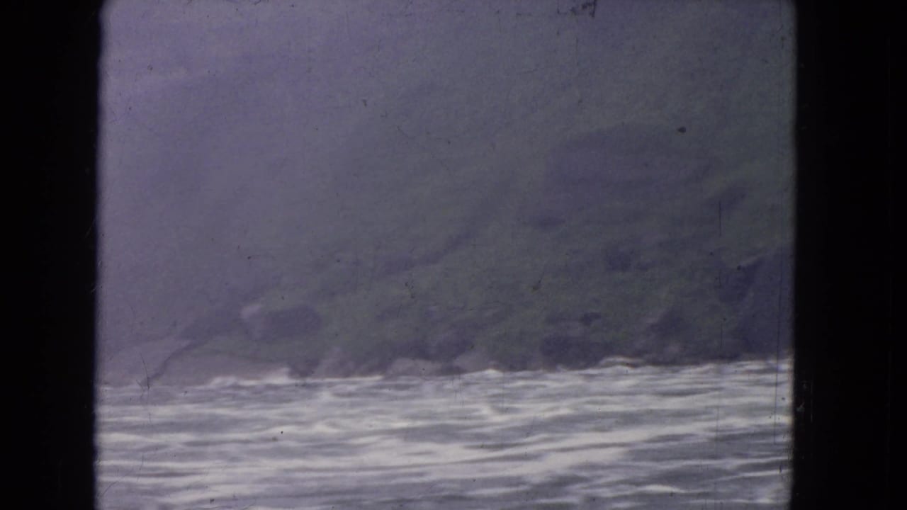 Water and hazy shoreline seen through a dark window frame.