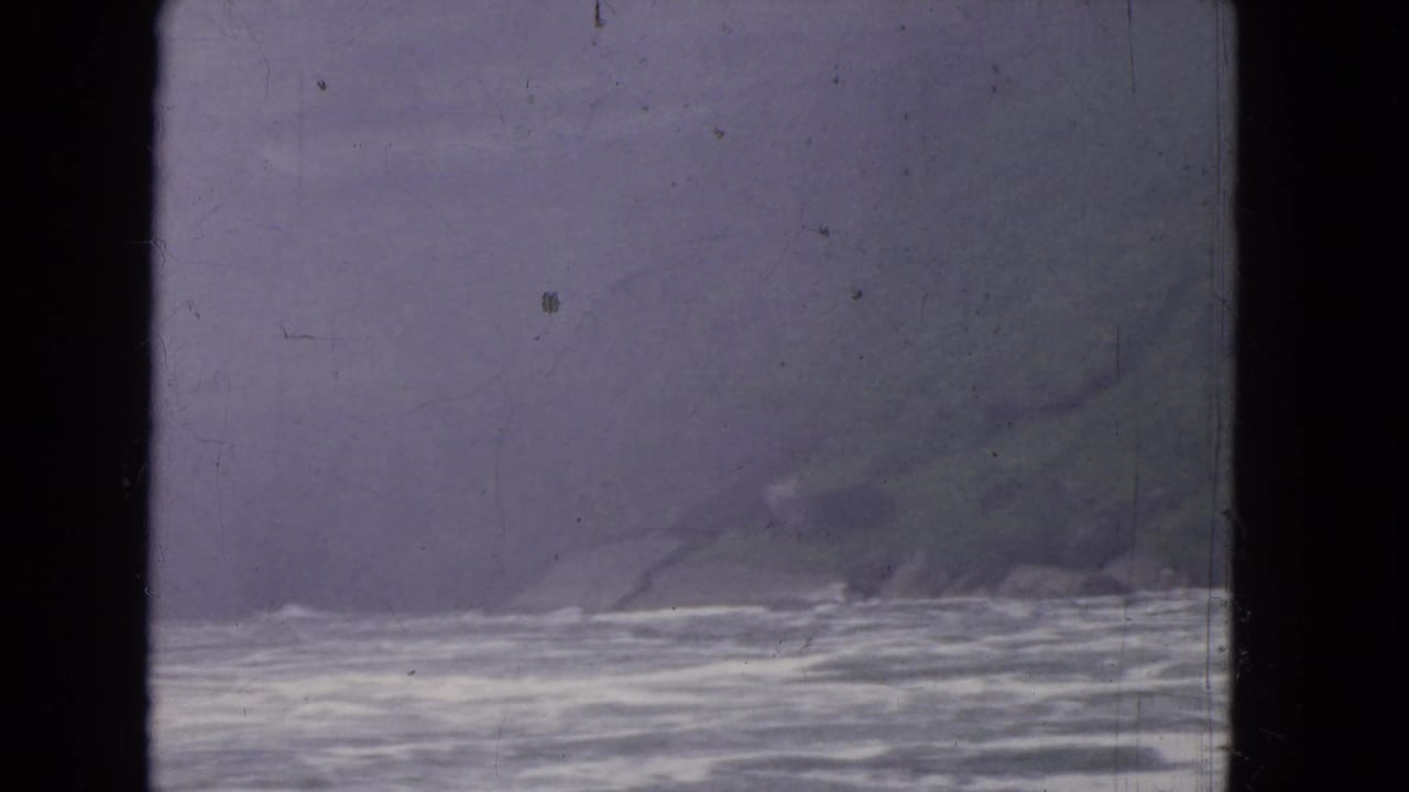 A hazy waterside view, likely from the 1964 Niagara Falls travel reel, seen through a dark-framed window.