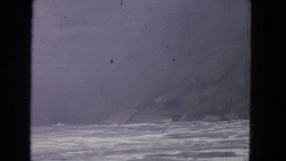 A hazy waterside view, likely from the 1964 Niagara Falls travel reel, seen through a dark-framed window.