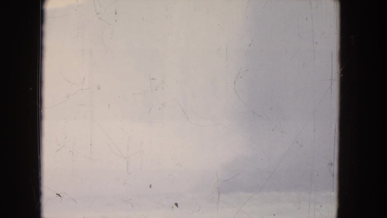 Misty distant waterfall view with pale sky and visible 8mm film wear.