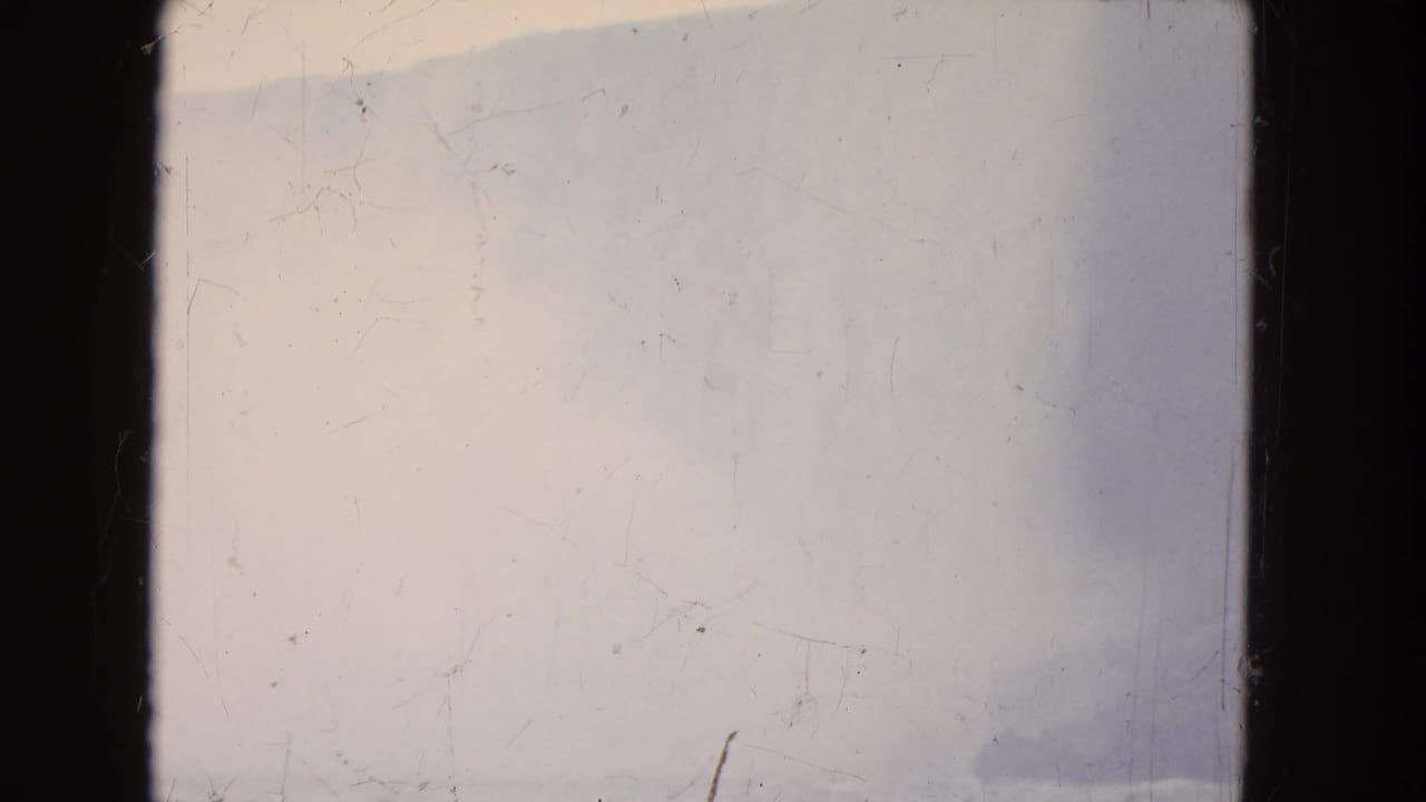 1964 Niagara Falls home-movie frame with pale mist, faint waterfall contours, and strong visible 8mm surface wear.