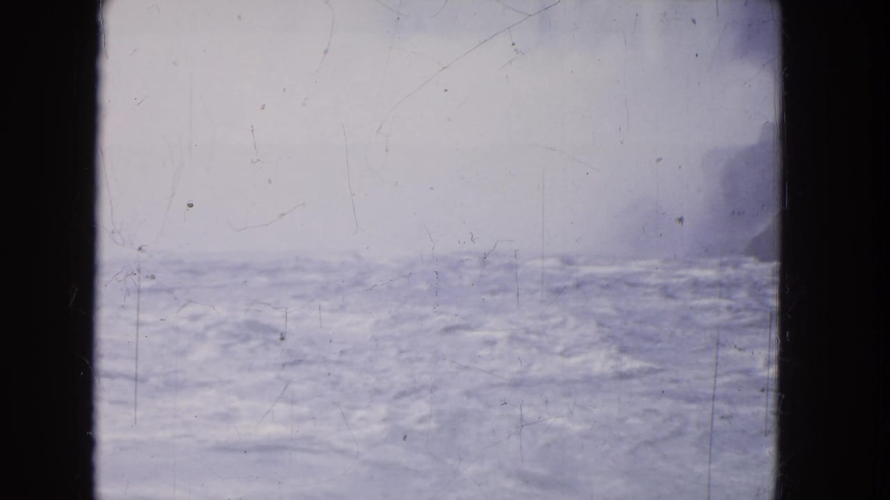 Blue-gray rushing water under pale mist with a dark frame edge at left.
