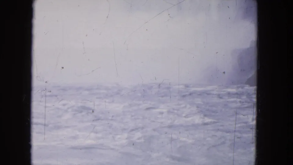 Blue-gray rapids or river surface at Niagara Falls appears through haze, with a dark vertical frame edge on the left.