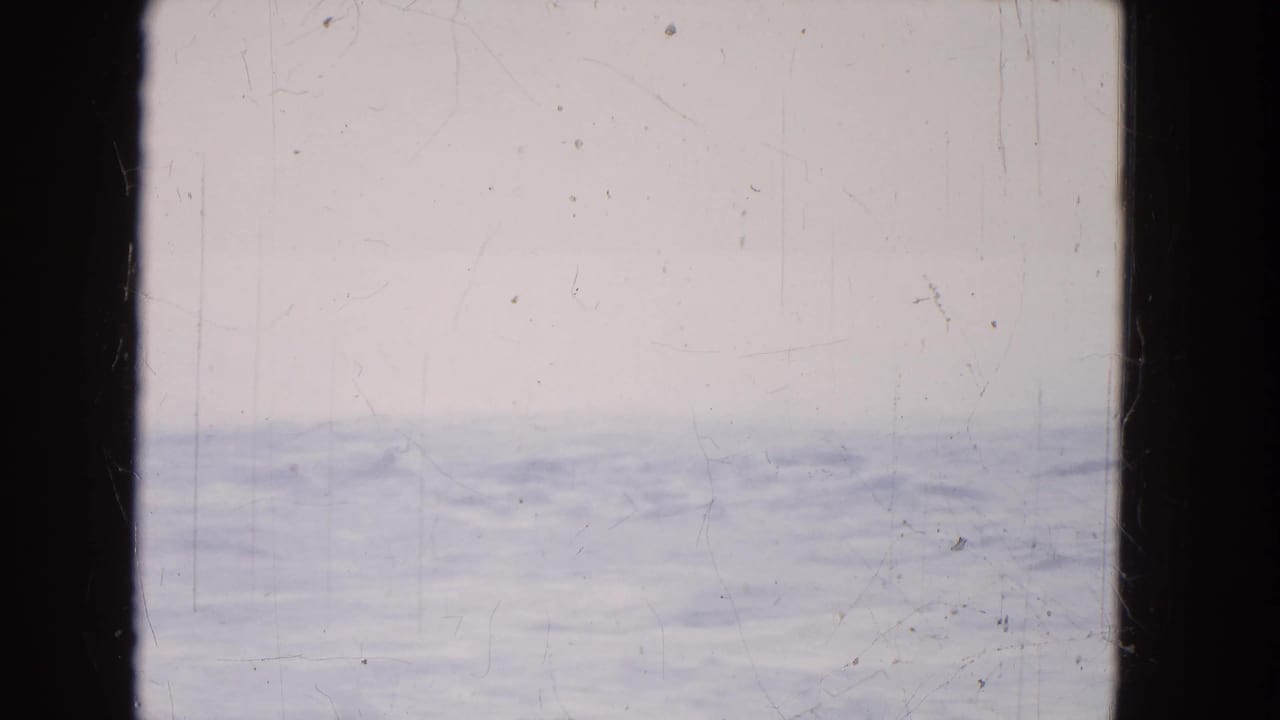 1964 8mm home-movie view near Niagara Falls showing pale water and a hazy horizon through dark window or film-frame borders.