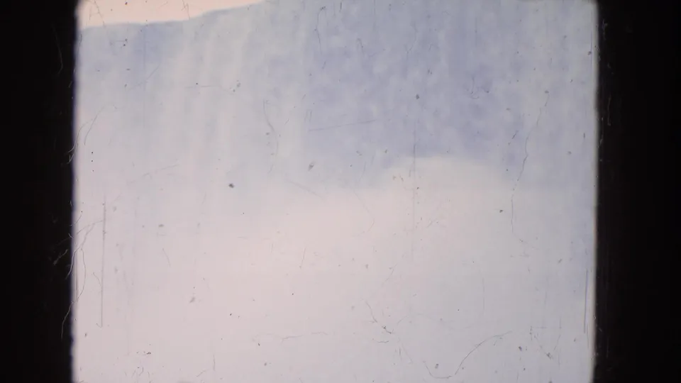 1964 8mm home-movie frame, likely Niagara Falls area, showing pale sky and a low water band with visible film scratches.