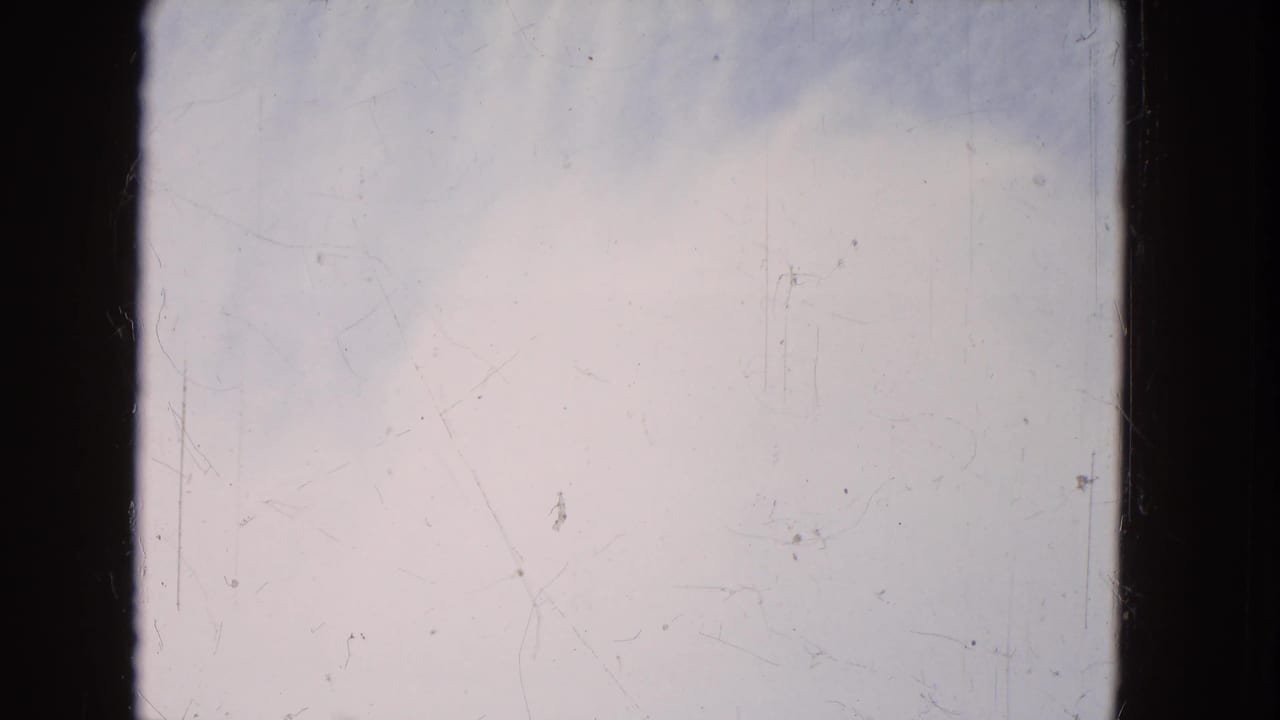 Soft pale sky and low water texture bordered by dark film edges.