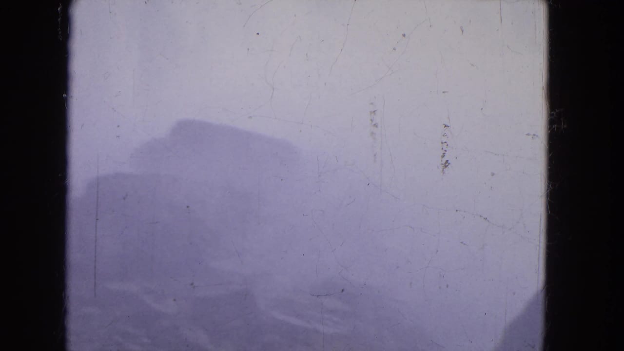 The Niagara Falls home-movie frame shows dark rock shapes below a misty water surface, with scratches and blue-purple exposure shift.