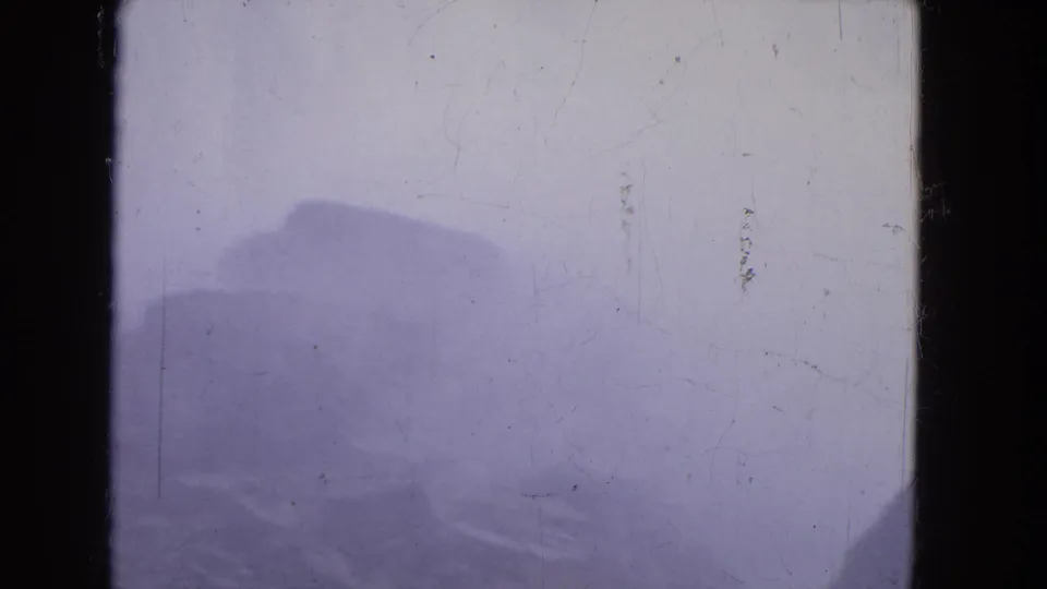 The Niagara Falls home-movie frame shows dark rock shapes below a misty water surface, with scratches and blue-purple exposure shift.