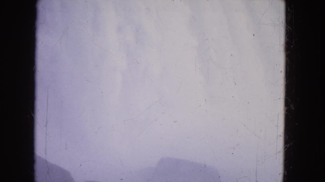 The final 1964 Niagara Falls frame is largely mist and pale spray, with faint rock silhouettes at the bottom and worn 8mm surface marks.