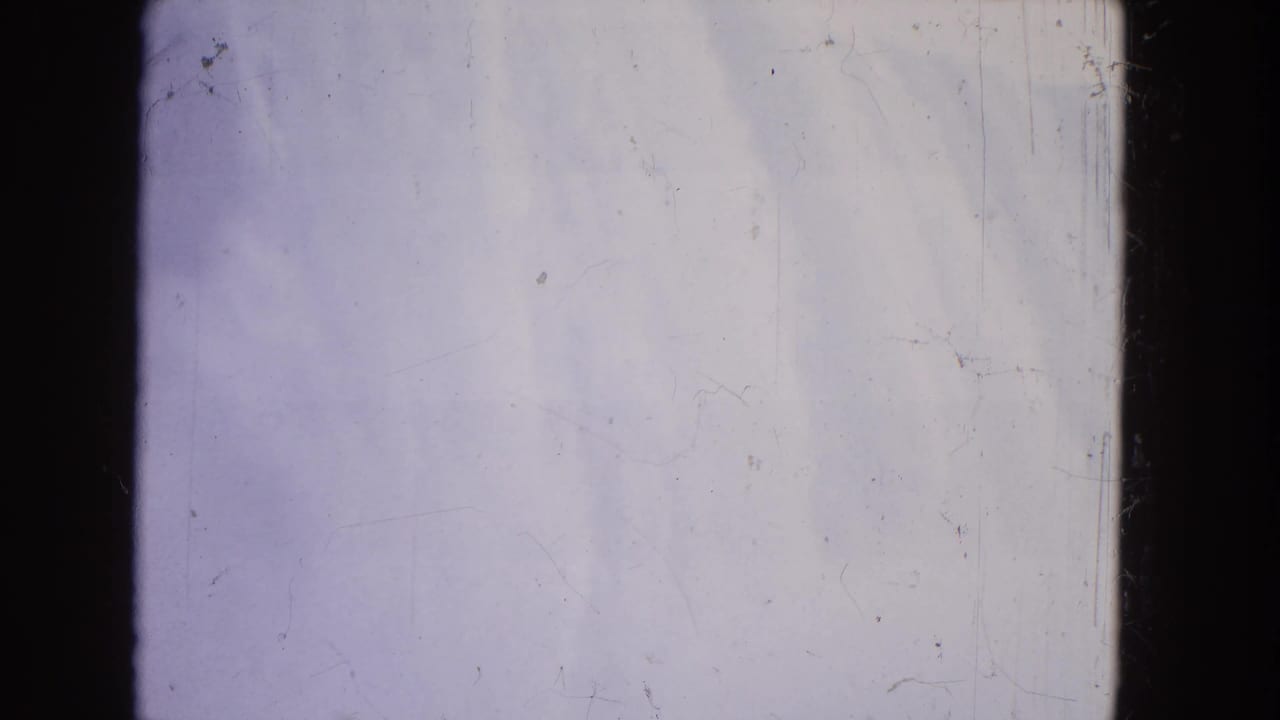 1964 Niagara Falls 8mm frame showing pale water and mist, blue-purple tint, dark gate edges, and film scratches.
