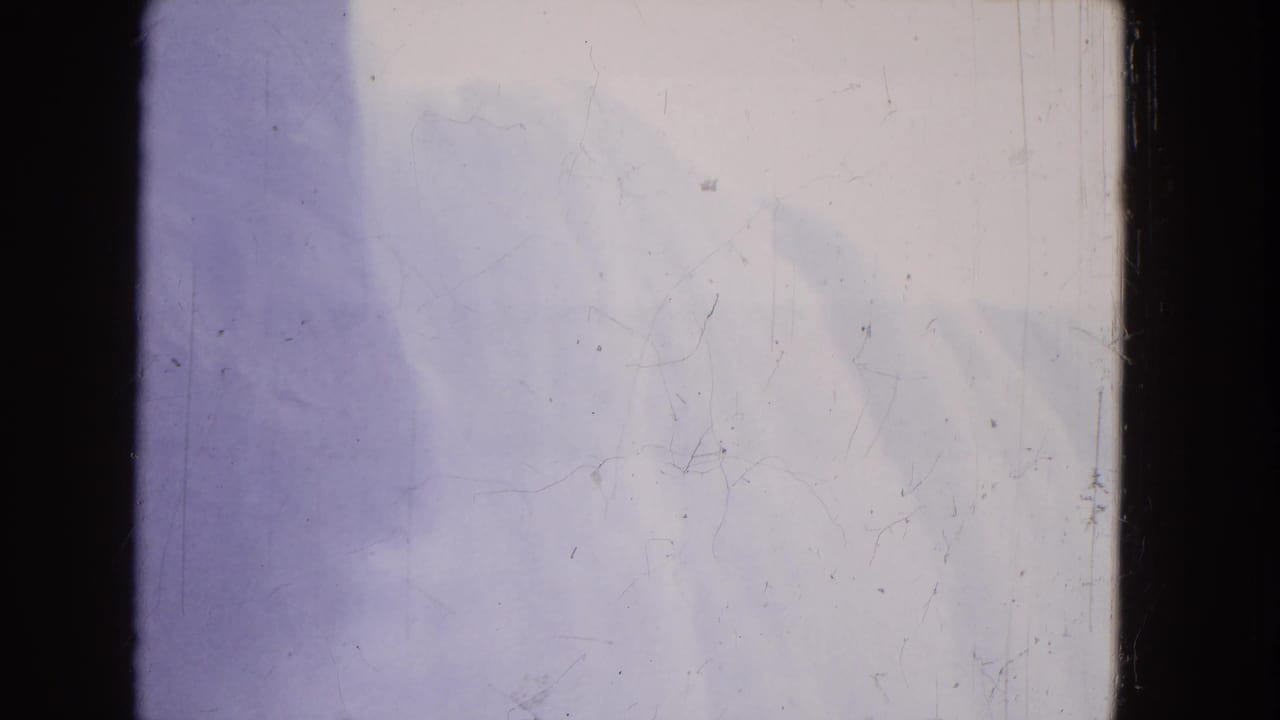 Bright waterfall mist and pale water with purple shadowing and film scratches.