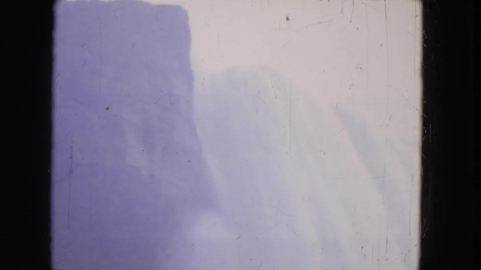1964 Niagara Falls 8mm frame showing soft pale water, blue-purple mist, dark film edge, dust, and scratches.