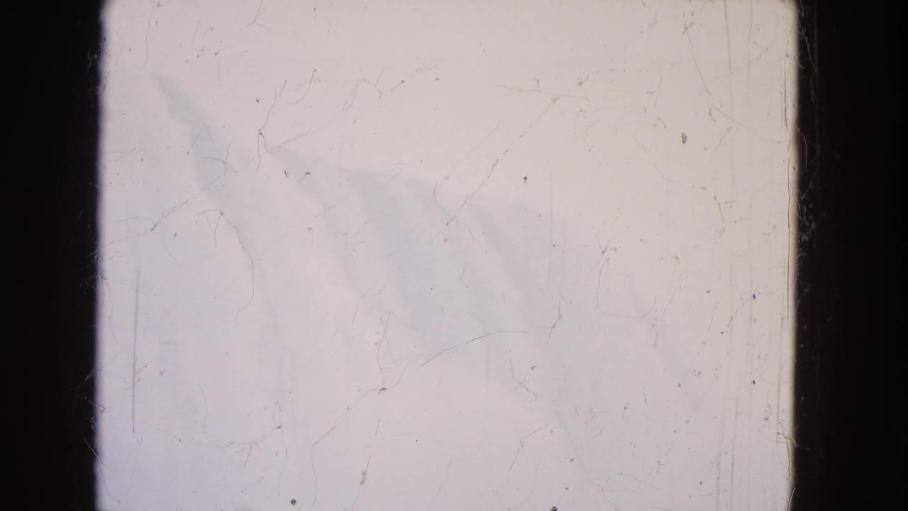 1964 8mm frame of Niagara Falls seen faintly through mist, with pale sky, water, and visible film wear.