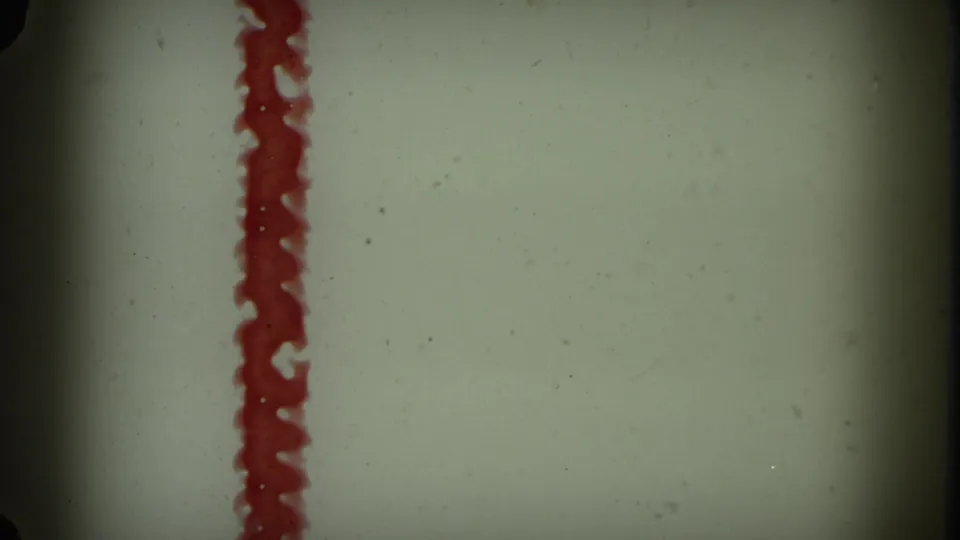 1964 8mm frame with a vertical red leader marking against a pale field, bordered by dark gate shadows and visible film specks.