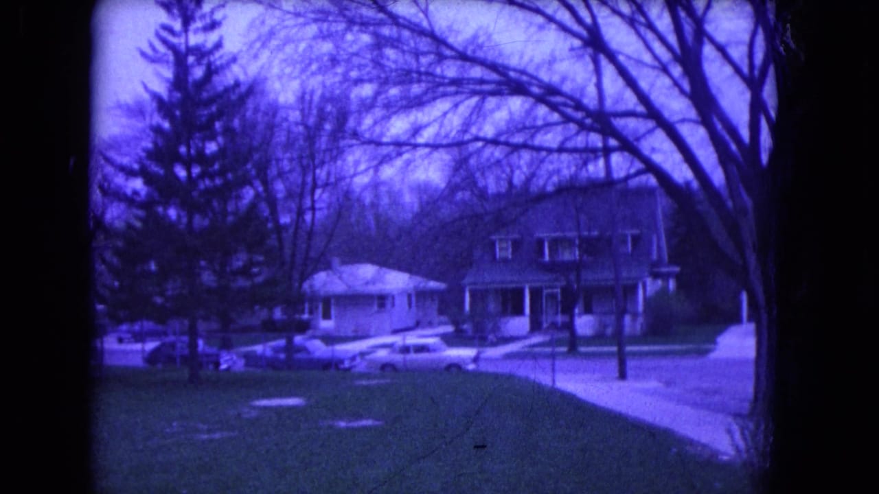 1964 Niagara Falls, USA suburban street with detached homes, bare trees, a lawn, sidewalk, and parked mid-century cars.