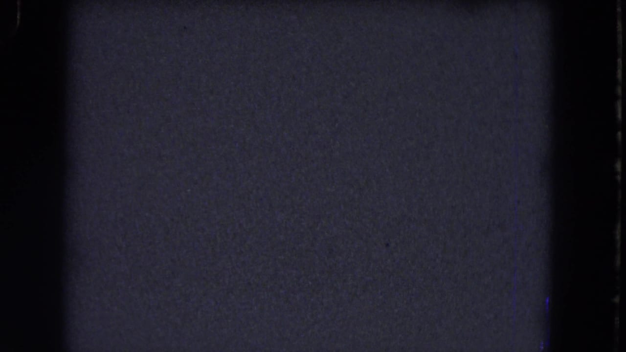 Blue-gray underexposed 8mm frame from the 1964 Niagara Falls reel, bordered by dark gate edges and visible film grain.