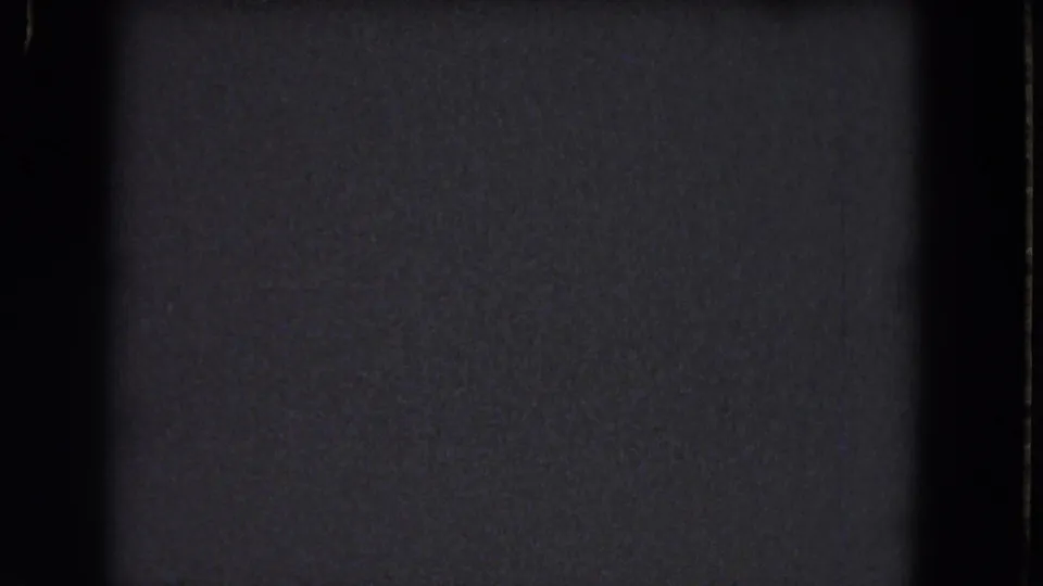 1964 8mm frame from the Niagara Falls clip with dark static texture, black film-edge shadows, and no visible people or setting.