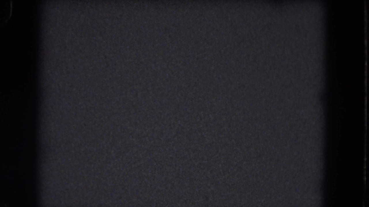 Dark 8mm frame with visible grain, black borders, and faint specks.