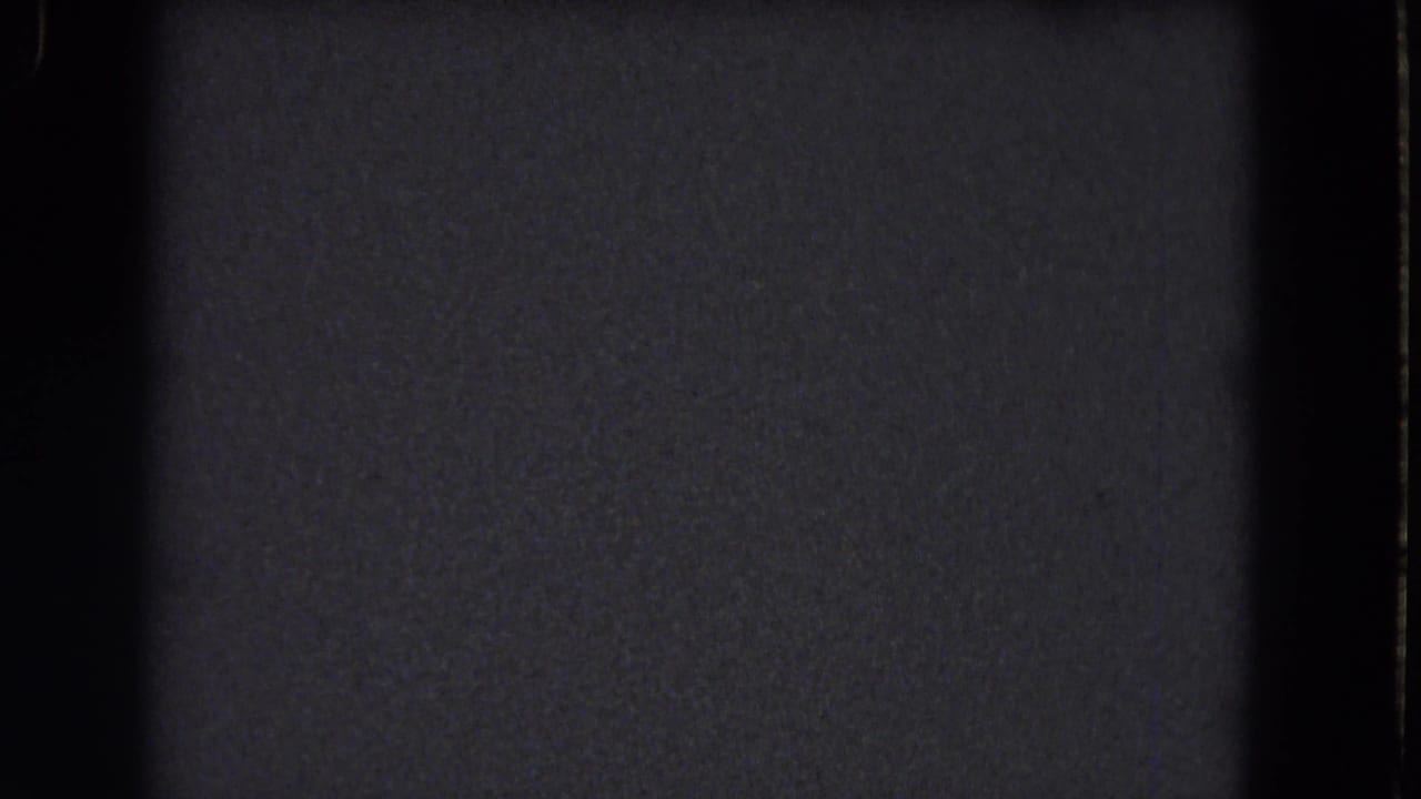 Underexposed 8mm frame from the 1964 Niagara Falls reel, with dark texture, grain, and no identifiable subject.