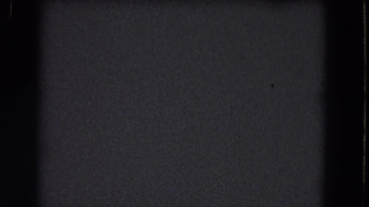 Nearly black 8mm frame with grain, gate edges, and a faint grey exposure area.