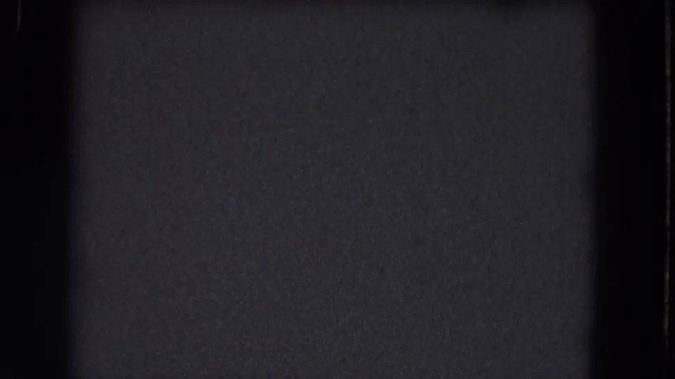 Dark 1964 home-movie frame with broad 8mm gate edging, grain, faint bluish-grey exposure, and small specks.