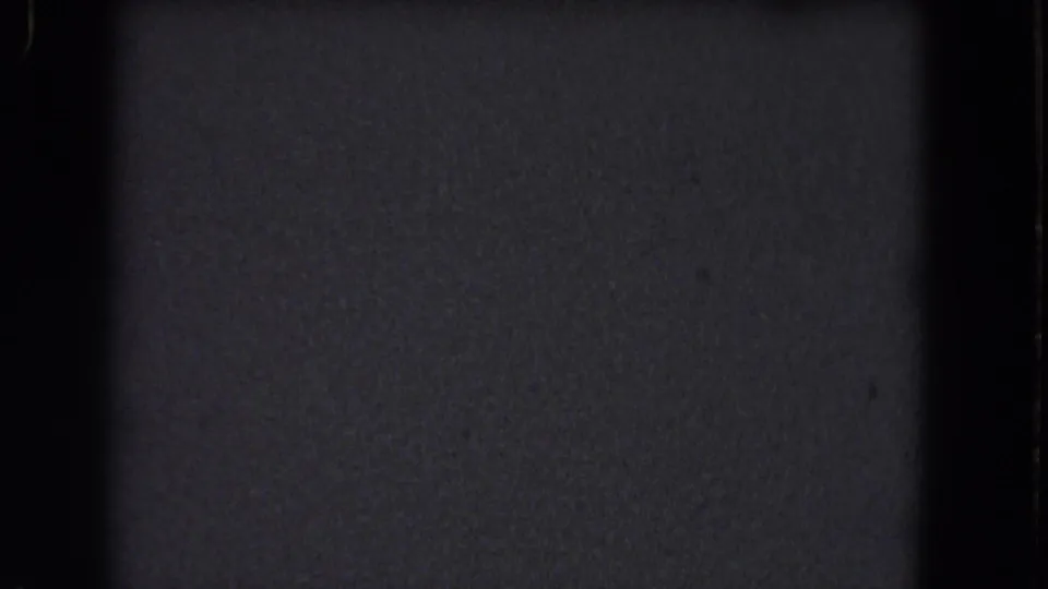 Underexposed 8mm frame from metadata-described 1964 Niagara Falls footage, showing grain, dust, and a vertical gate edge without identifiable scenery.