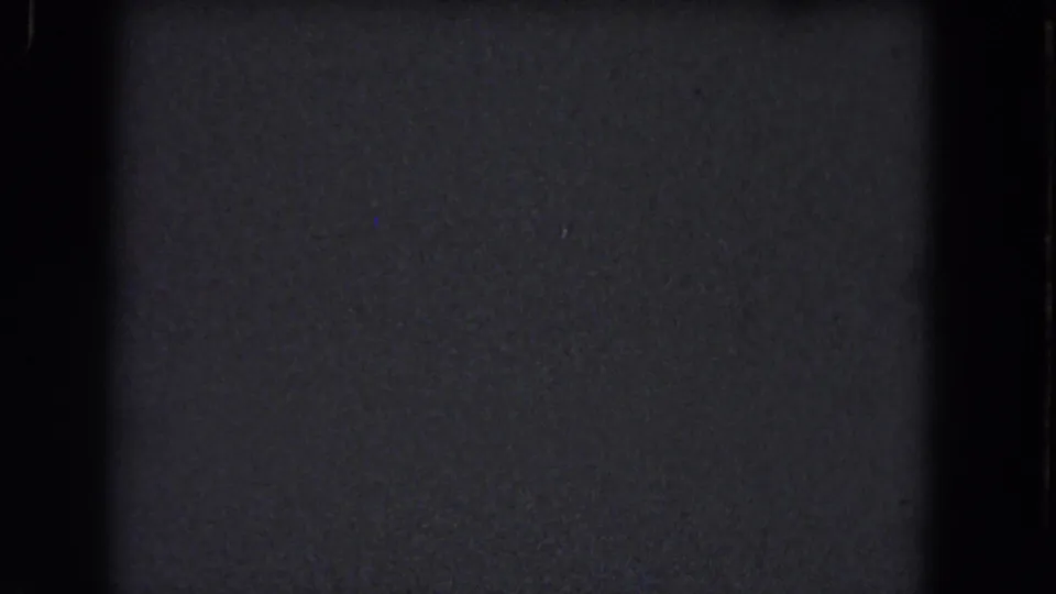 A dark 8mm frame from the 1964 Niagara Falls reel, dominated by grain, vertical gate shadow, and faint dust particles.