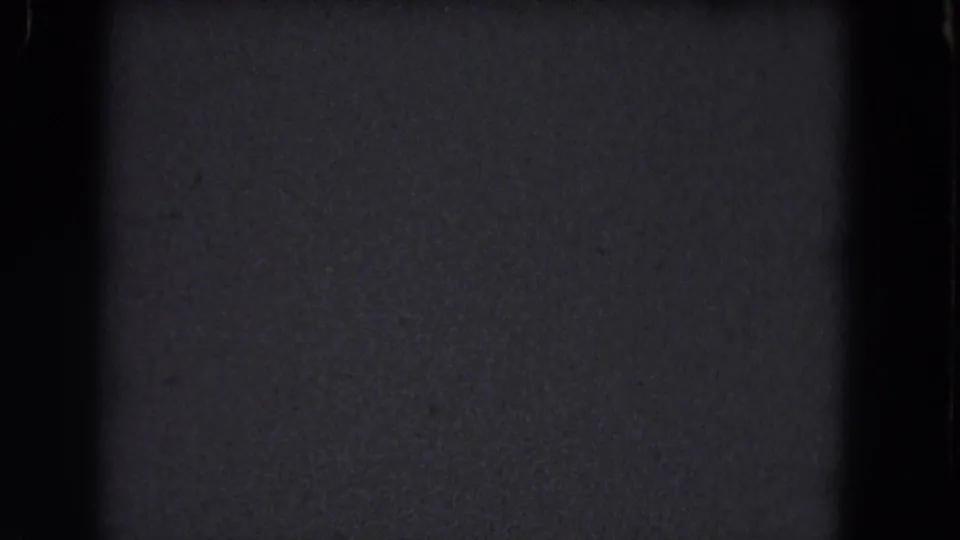 Dark 1964 8mm footage with coarse grain, edge shadows, dust, and a subtle horizontal exposure change across the frame.